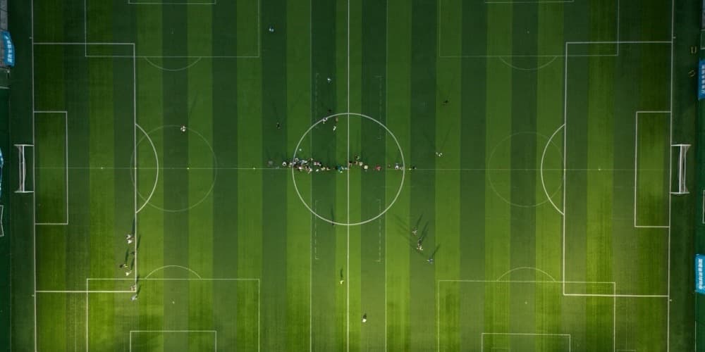 Fotballbane sett ovenfra med spillere samlet rundt midtsirkelen